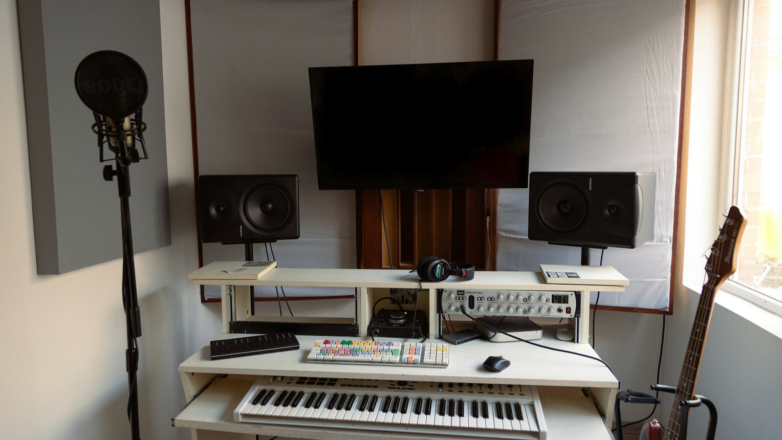 La cabine du studio Soundsitive : micro à filtre anti-pop, clavier et guitare prêts pour une session